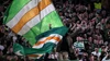 Ein treuer Fan schwenkt auf der Tribüne enthusiastisch eine riesige grün-weiß-orangefarbene Flagge inmitten der lautstarken Fankurve von Celtic Glasgow.